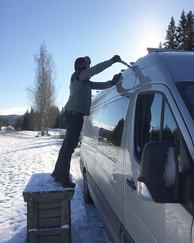 Clearing snow from the roof of our van to ensure enough solar for winter van life