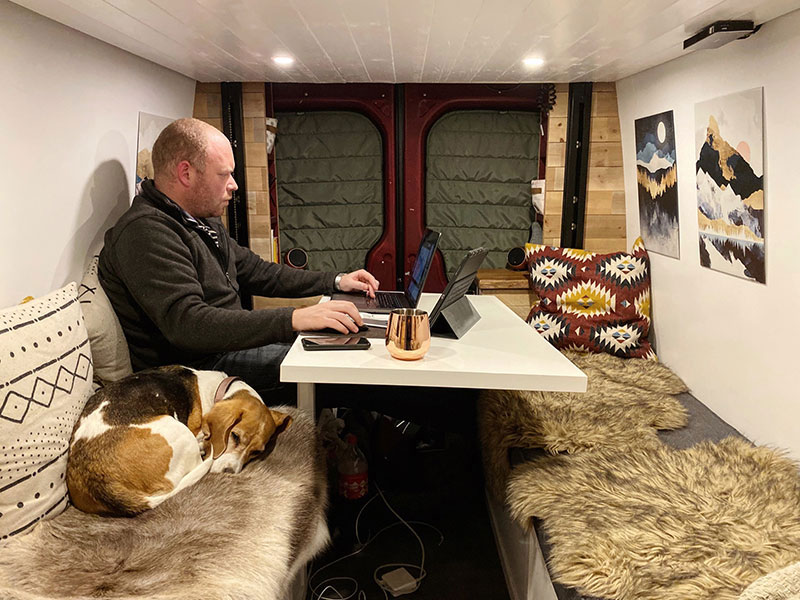 Will and Piglet sitting beneath our Happijac bed showing one of our van build mistakes blocking our ceiling fan