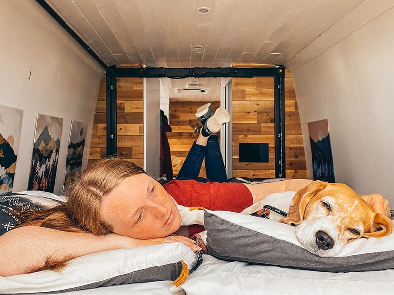 Lying on bed in camping slippers in self converted campervan with dog